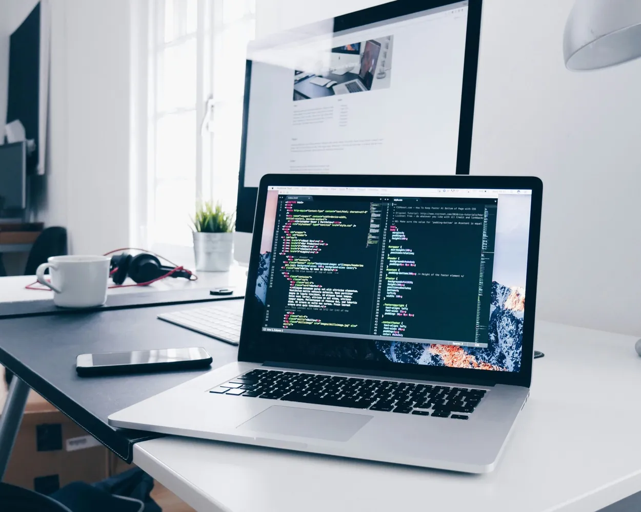 Engineer's workstation with code on a laptop and a large monitor
